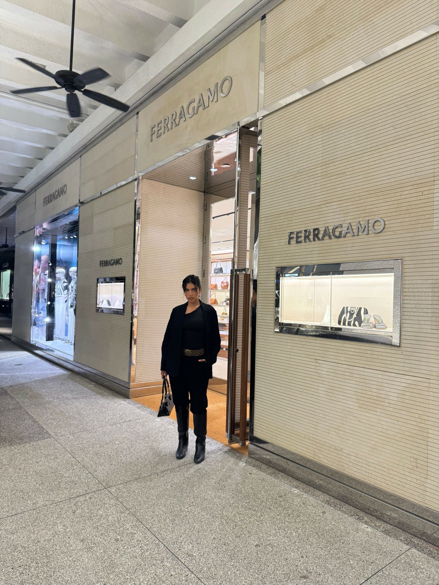 Person standing in front of a store entrance with a sign reading 'FERRAGAMO'.