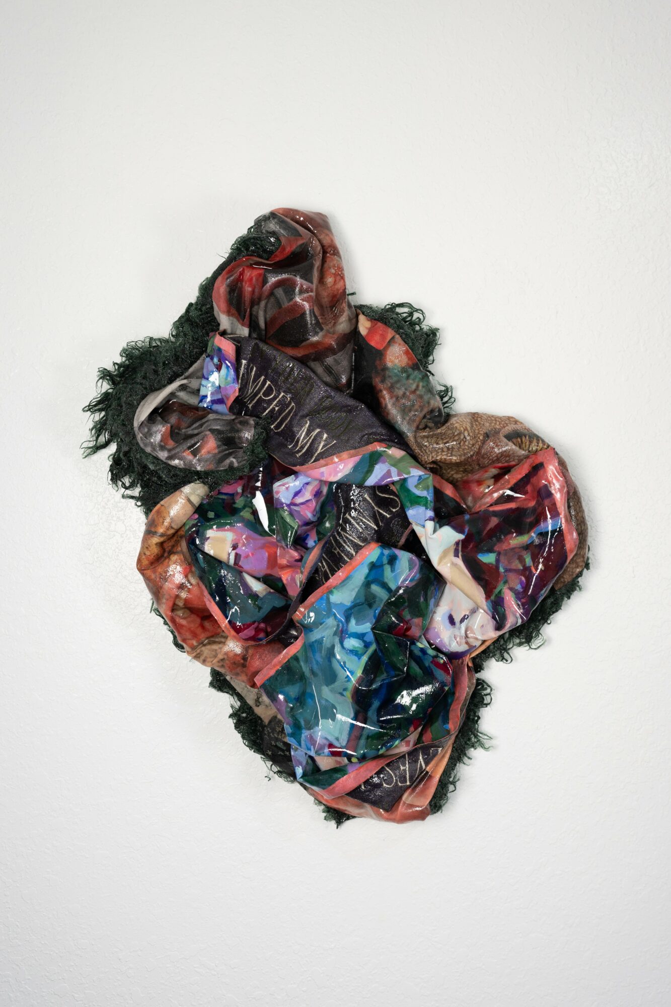 Colorful, crumpled fabric with shiny and matte textures, arranged on a plain white background.