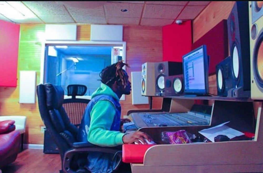 Person working at a music production station with speakers and a computer monitor, in a colorful room.
