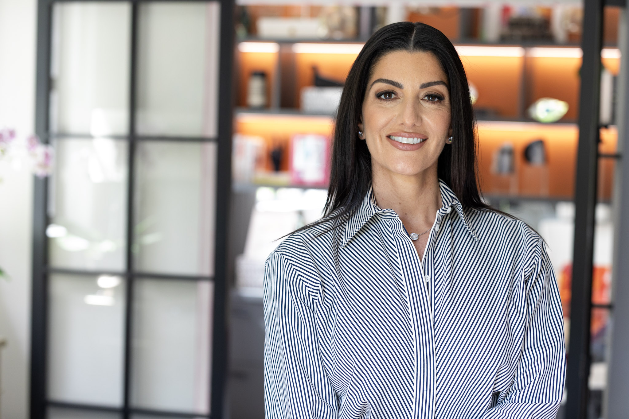 Smiling woman with dark hair in a striped shirt in a modern office setting