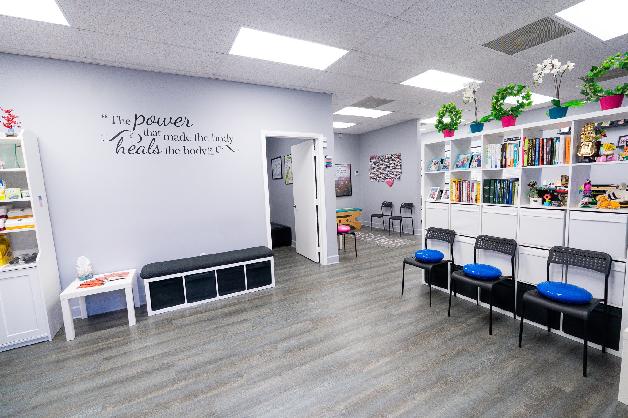Room with chairs, bookshelves, and wall quote, bright lighting, and gray flooring.