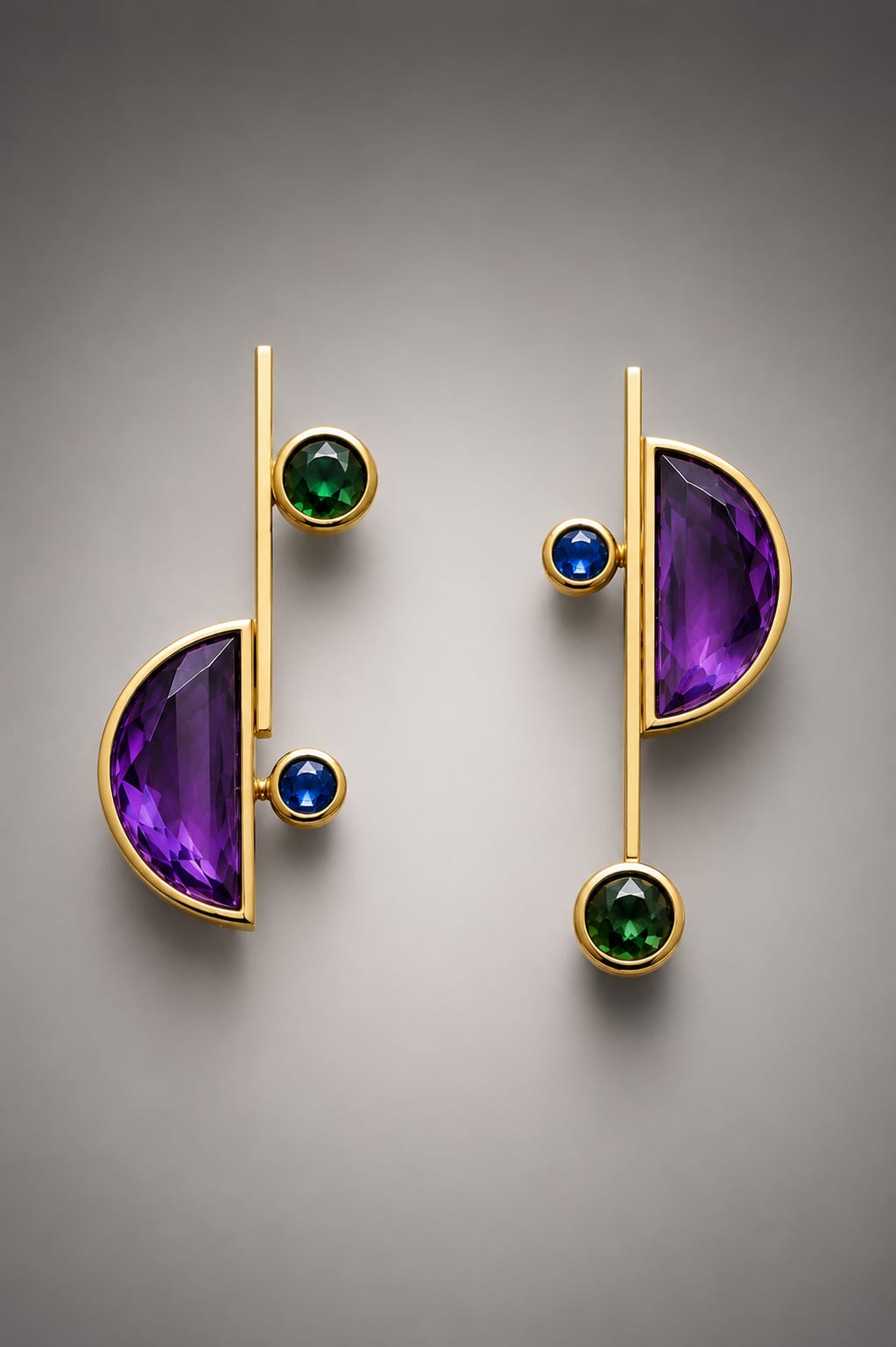 Pair of modern earrings with gold lines, purple semi-circles, and green and blue round stones, displayed against a gray background.