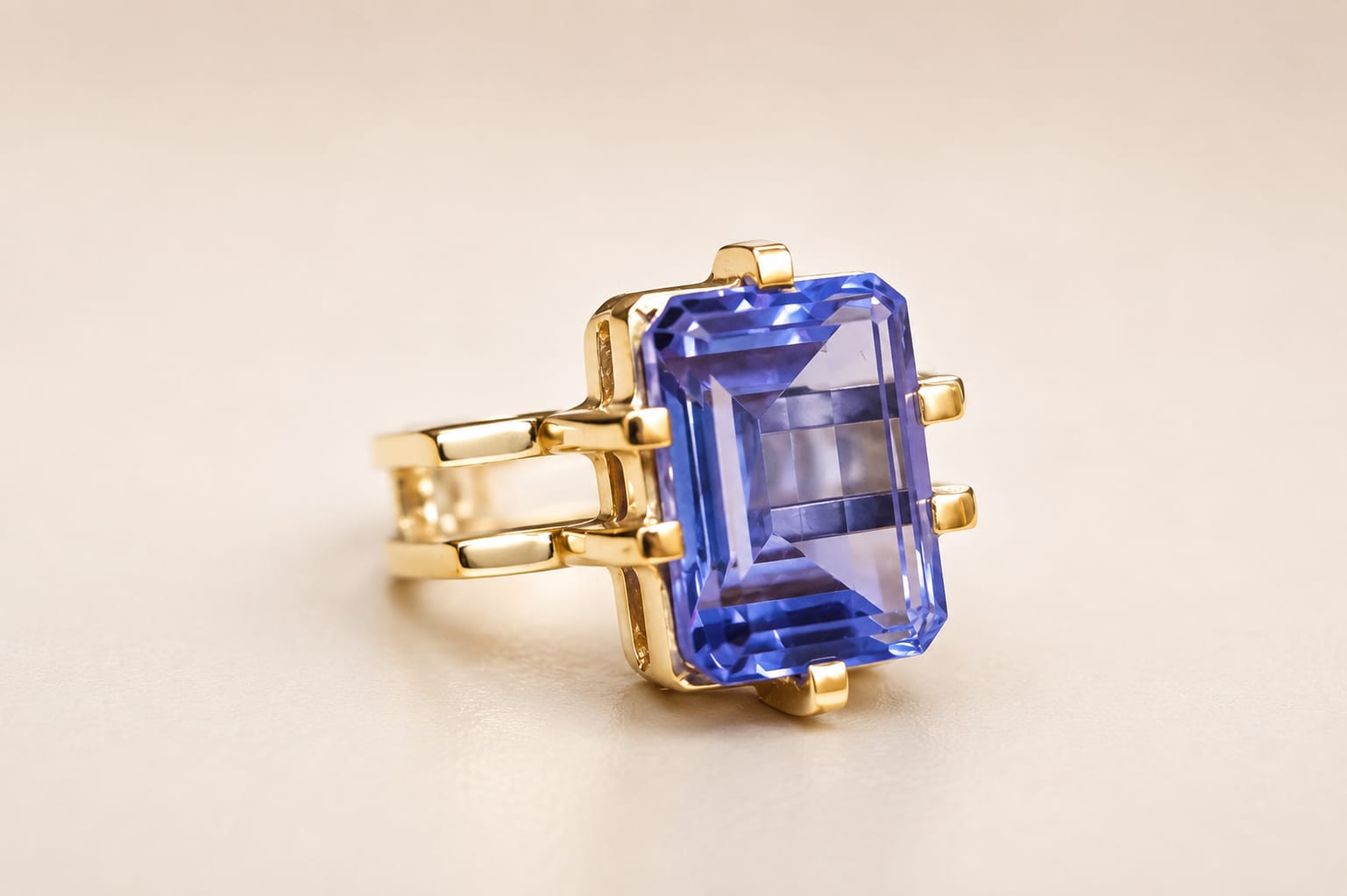 Gold ring with a large rectangular blue gemstone, set against a plain light background.