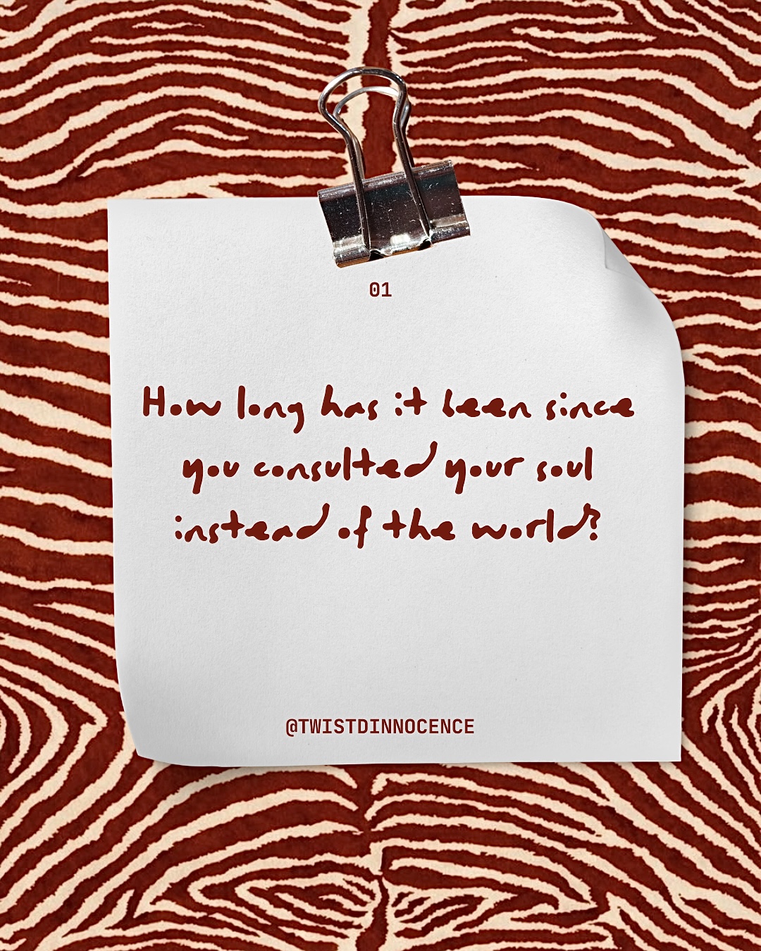 Note with handwritten text attached to a red and white patterned background, clipped with a binder clip.