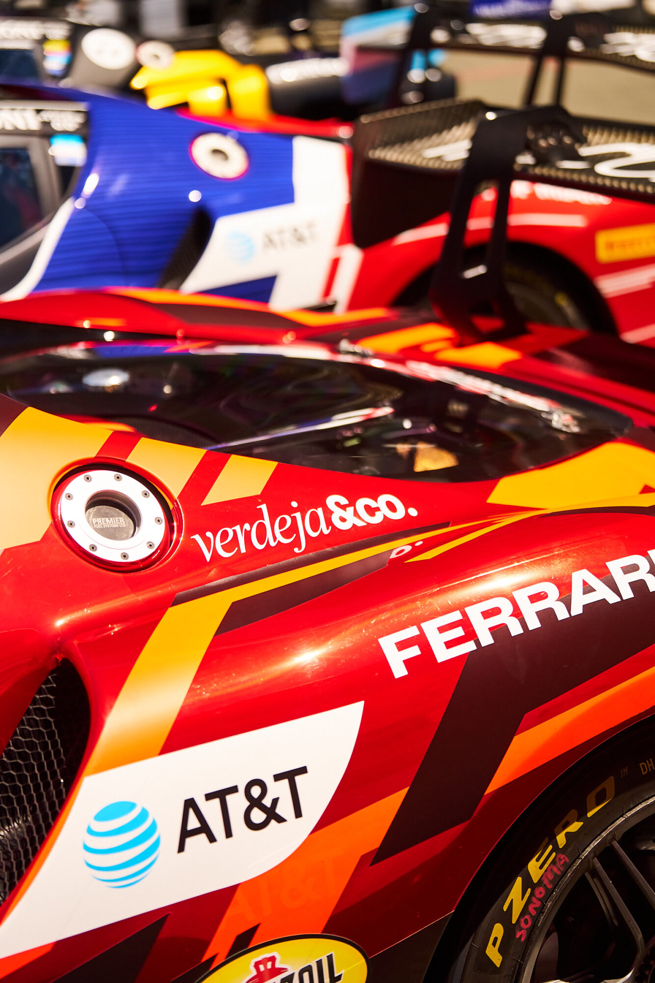 Close-up of red and yellow race cars with sponsor logos, parked side by side.