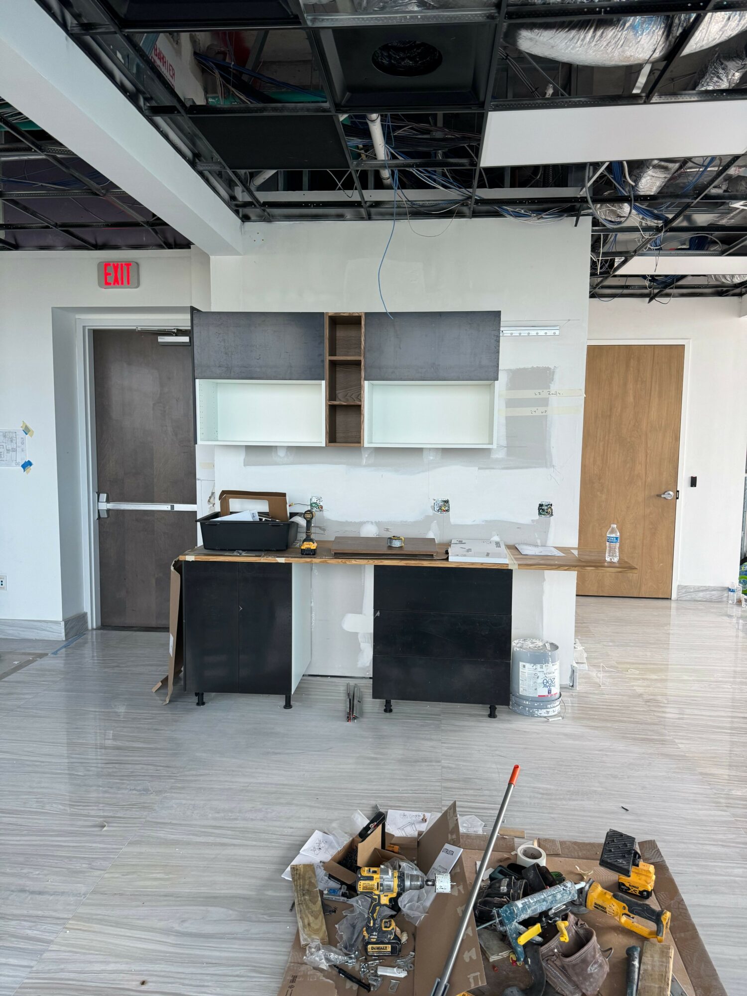 Modern interior with white shelving, black chairs, and a workspace, with tools on a nearby table.