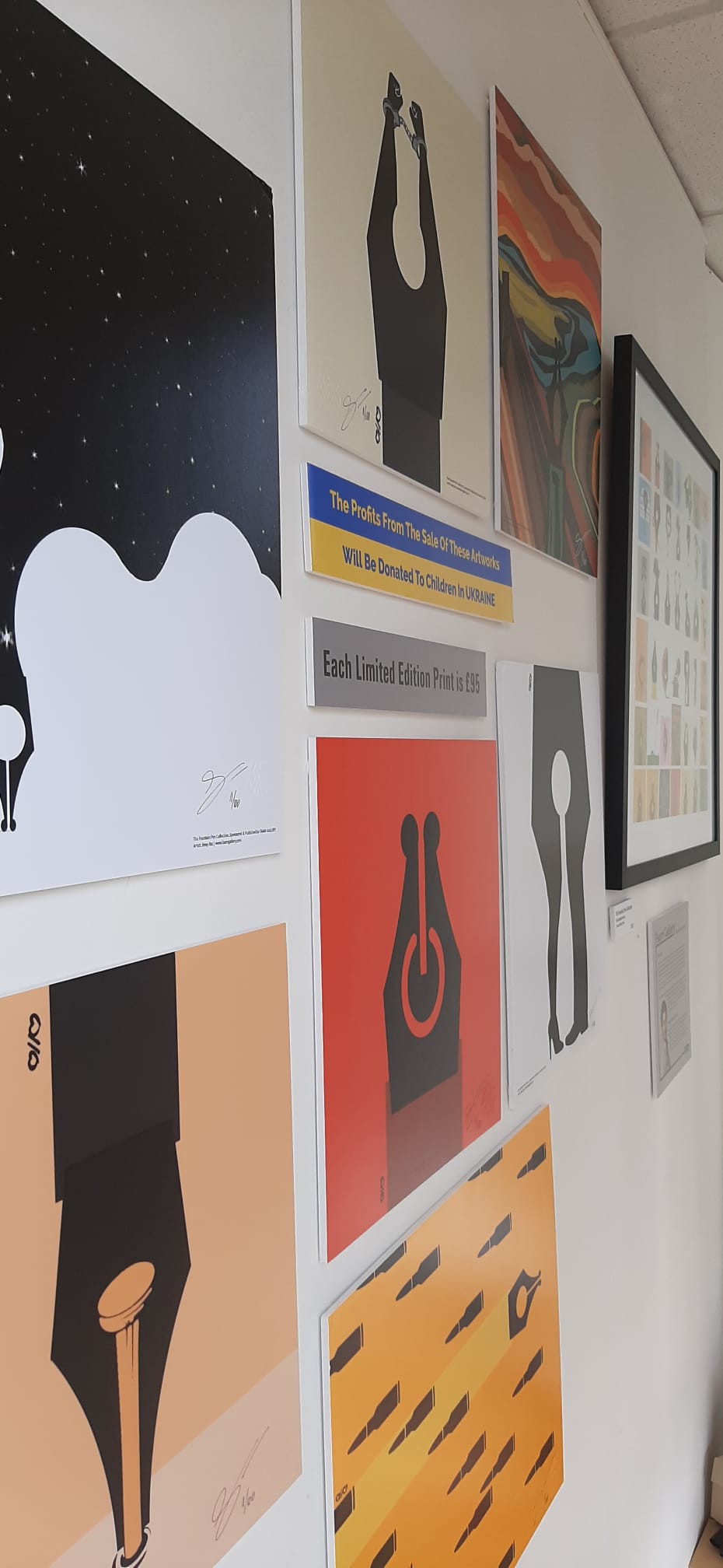 Gallery wall with various colorful posters and artwork, including a black and white bear, a black dress, and abstract designs.