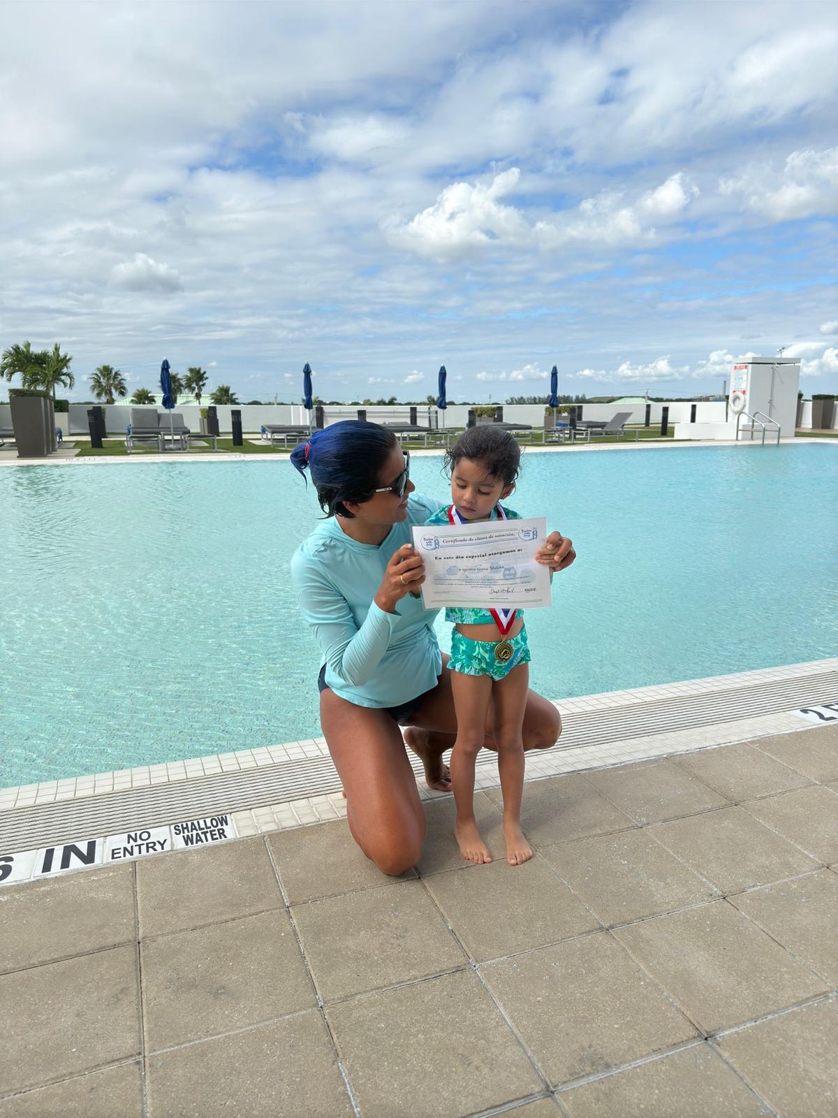 Adult and child reading a paper by a poolside with a city skyline and blue sky in background.
