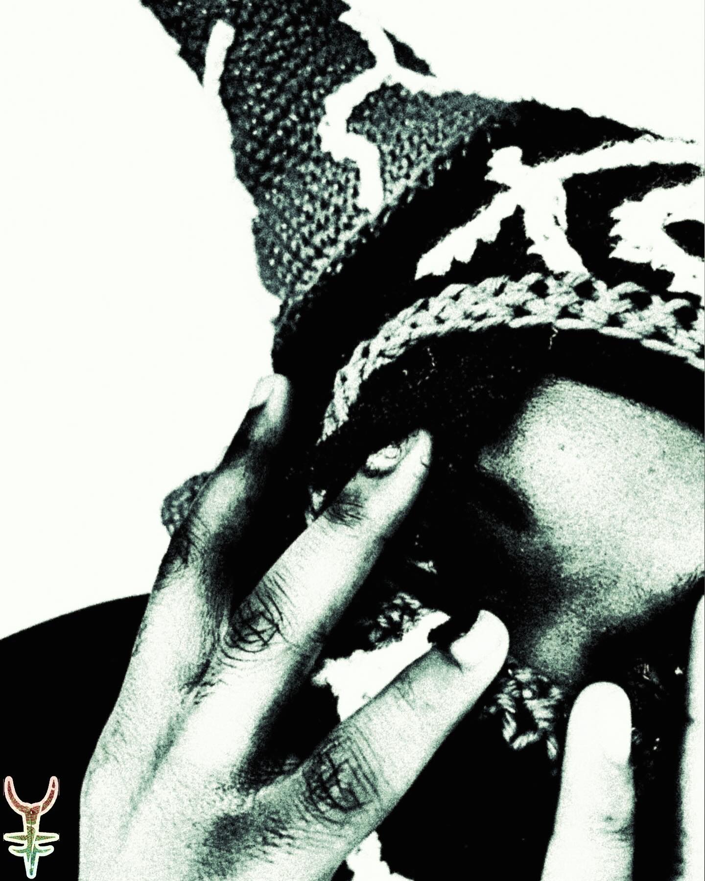 Person wearing a patterned headscarf, covering part of their face with hands, in black and white.