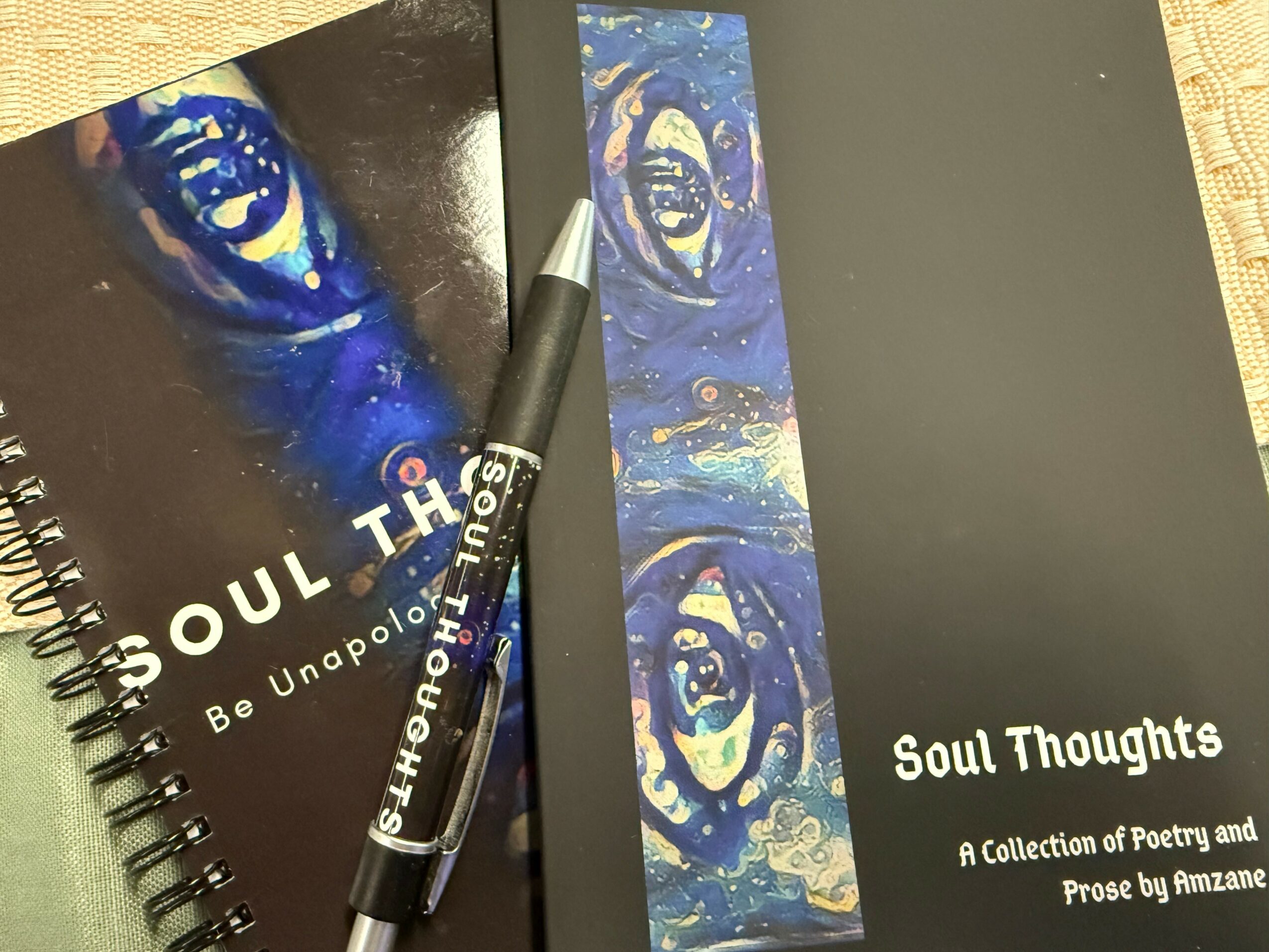 Two books titled 'Soul Thoughts' with a pen on top, one with a blue eye illustration and the other with abstract art.