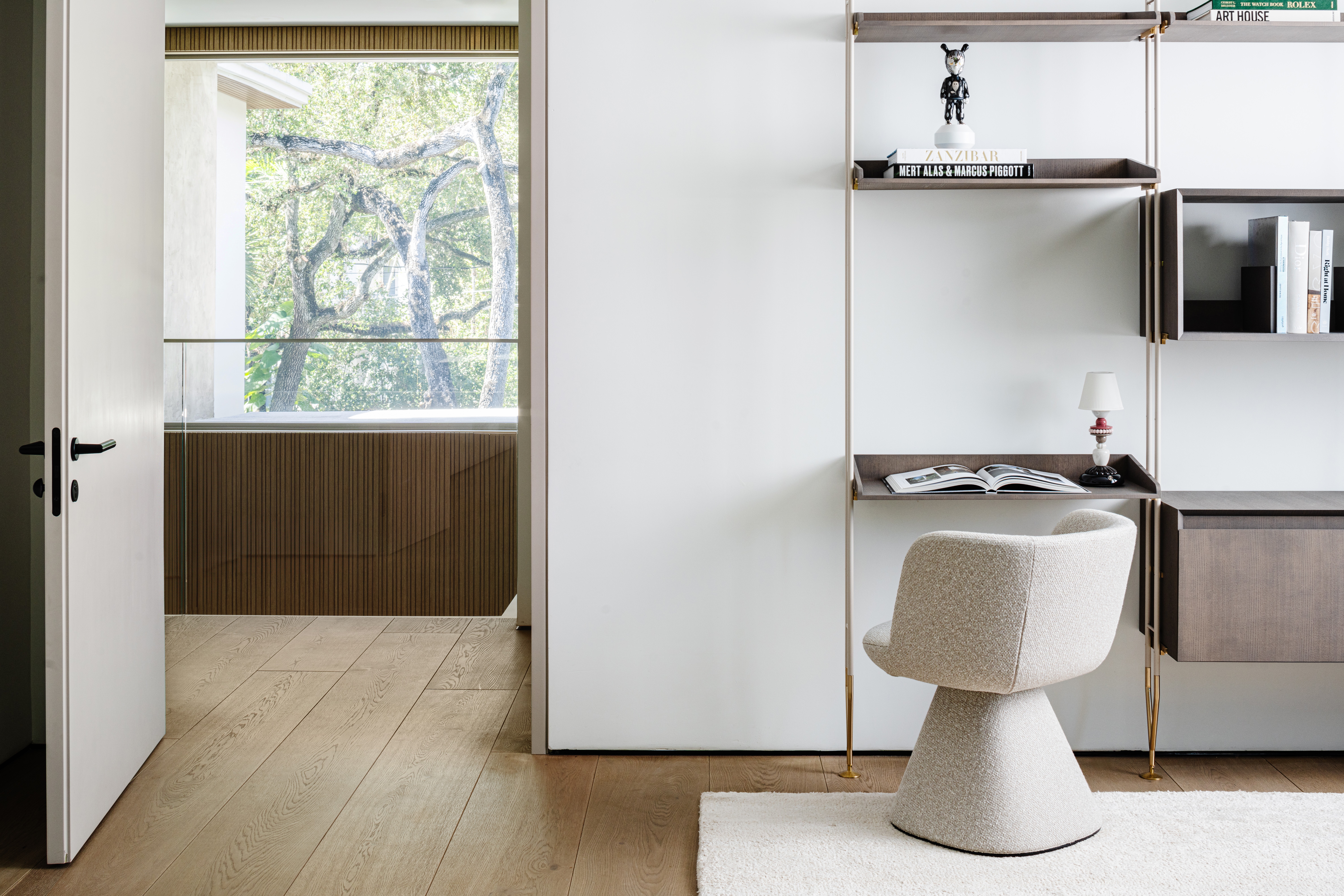 Interior room with a door open to a balcony and a white wall with shelves and a chair.